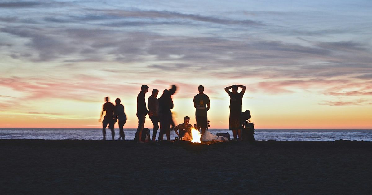 People have a beach party at sunset